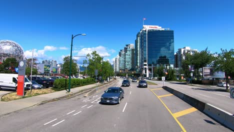 Vehicles-drive-by-science-museum-Science-World-in-Vancouver,-slow-motion