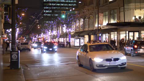 Cars-driving-on-a-commercial-street-in-downtown-Vancouver-at-evening-in-winter-time,-Slow-motion
