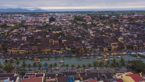 Luftaufnahme-Abend-Hyperlapse-Von-Hoi-An-In-Vietnam-Mit-Der-Stadt-Und-Beleuchteten-Booten-Mit-Laternen-Auf-Dem-Fluss