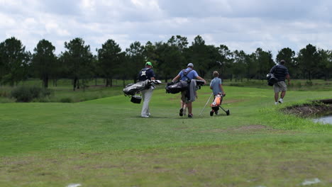 Three-men-walking-with-a-young-boy-on-a-golf-course-to-the-next-hole