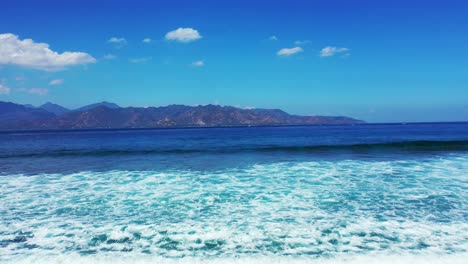 Ehrfürchtige-Weiße-Welle,-Die-Vom-Tiefblauen-Meer-In-Richtung-Der-Seichten-Türkisfarbenen-Lagune-Auf-Der-Meereslandschaft-In-Lebhaften-Farben-In-Indonesien-Kommt