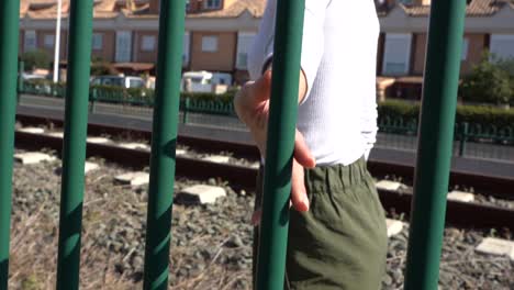 Girl-sliding-hand-on-railroad-protection-grid,-slow-motion