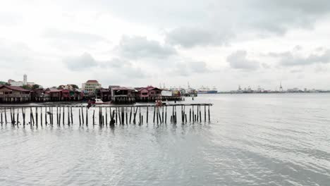 People-and-couple-enjoying-sitting-at-Tan-Jetty-in-the-Little-India-Quarter-of-the-city-at-low-tide,-Aerial-drone-dolly-out-shot