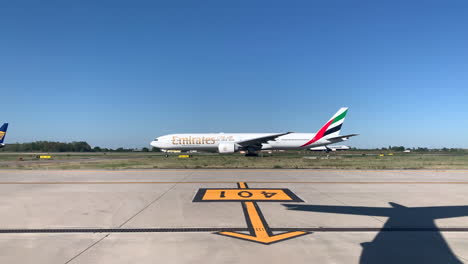 Avión-De-Pasajeros-En-La-Calle-De-Rodaje-Con-Aterrizaje-De-Avión-En-La-Pista-Detrás