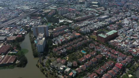 Fly-in-view-over-canal,-industrial-buildings-and-residential-buildings-with-roads,-parklands-and-canals