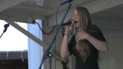 Woman-sings-on-stage-holding-microphone-at-gig