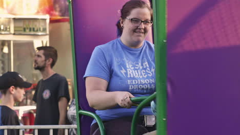 Young-boy-and-sister-spinning-and-laughing-on-ride-at-community-carnival,-Close-Up,-Slow-Motion