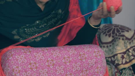Mujer-India-Sentada-Y-Enrollando-La-Lana-Roja-En-Una-Bola-Para-Prepararla-Para-Tejer