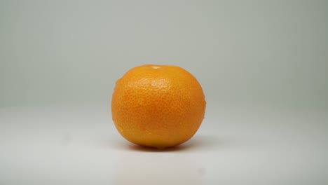 Frische-Orangenfrucht-Auf-Dem-Rotierenden-Tisch-Mit-Weißem-Einfarbigem-Hintergrund---Nahaufnahme