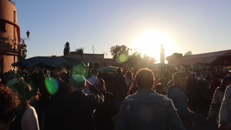 Große-Menschenmengen-Durchstreifen-Die-Straßen-Von-Marrakesch-Marokko-Mit-Sonnenaufflackern-Im-Hintergrund