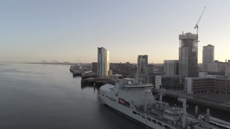 RFA-Navy-Tiderace-military-tanker-on-Liverpool-cityscape-waterfront-at-sunrise-aerial-pull-back-view