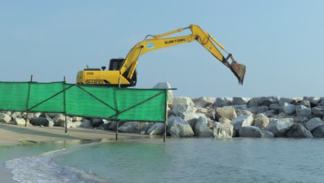 Schwere-Grabmaschinen,-Bagger,-Die-Eine-Felswand-Bauen,-Um-Den-Hafen-Vor-Stürmen,-Großen-Wellen-Oder-Einem-Tsunami-Zu-Schützen