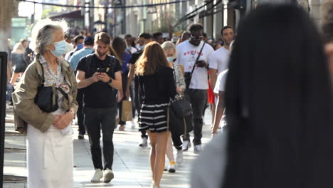 Alone-old-french-lady-with-protective-face-mask-inside-the-crowd-of-tourists-walking-on-the-sidewalk-without-respecting-sanitary-distances---Champs-Elysee