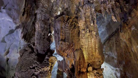 Una-Enorme-Formación-De-Estalagmitas-Se-Eleva-Desde-El-Suelo-De-La-Cueva-Cuando-Un-Visitante-Camina-Hacia-La-Derecha,-Inclina-Hacia-Arriba-Y-Revela-La-Toma