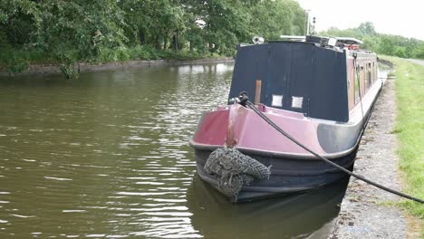 British-long-canal-narrow-boat-front-moored-along-scenic-English-marine-countryside-waterway