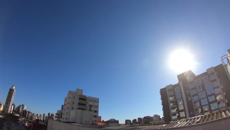 timelapse-of-the-sunset-descending-behind-a-building-in-são-paulo,-strong-colors-and-very-blue-sky