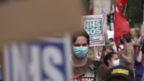 Hunderte-Von-Mitarbeitern-Des-Nationalen-Gesundheitswesens-Und-Schlüsselkräfte,-Die-Gesichtsmasken-Tragen,-Marschieren-Mit-Verschiedenen-Plakaten-Und-Singen-Zum-Protest-Gegen-Soziale-Distanzierung-Der-Lohngerechtigkeit
