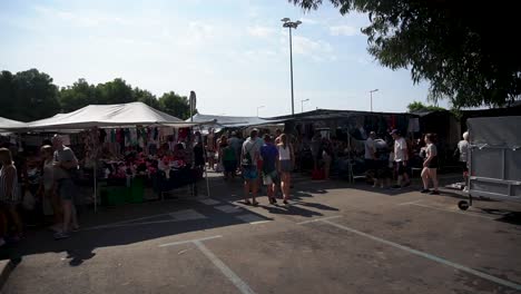 Gente-Caminando-Y-Pasando-Por-Las-Tiendas-En-Un-Mercado-Local-En-Calig,-Valencia,-España---Plano-General,-Lapso-De-Tiempo