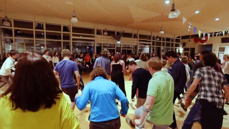 A-Big-Group-Of-Young-Active-People-Forming-A-Circle-Cheerfully-Dancing-During-A-Youth-Conference-Held-In-Waldorf-School-In-Netherlands---Medium-Shot