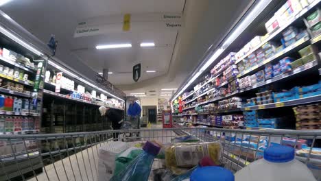 Inside-supermarket-shopping-cart-pushing-trolley-down-chiller-aisle-as-customers-shop-during-corona-virus-pandemic