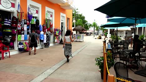 A-female-tourist-in-a-gently-flapping-dress-captures-footage-of-a-corner-cafe-during-her-trip-to-Cozumel-Island,-Mexico