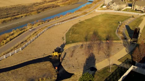 Construction-crew-paving-a-park-trail-with-asphalt---aerial-view-at-sunset
