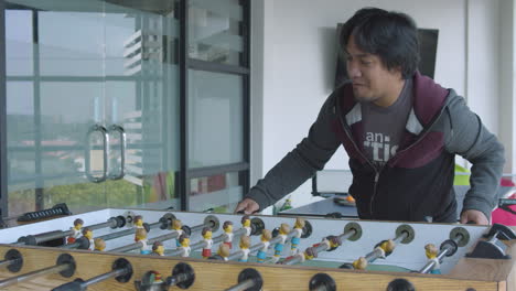 Man-Enjoying-The-Table-Football-Game-Inside-The-Game-Room-Of-A-Modern-Corporate-Office
