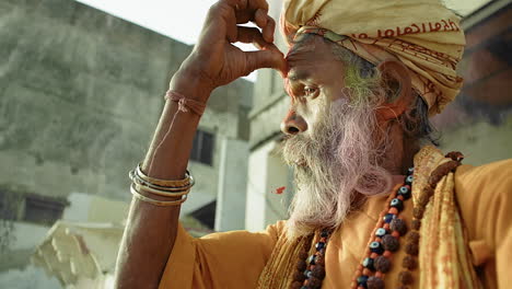 Man-wearing-a-headdress-with-his-thumb-pressed-to-his-forehead