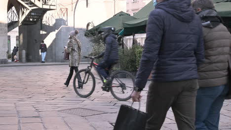 Personas-Con-Máscaras-Caminan-Por-Las-Calles-De-La-Ciudad,-Restaurante-Bar-Con-Plantas-Al-Aire-Libre-En-El-Fondo-En-Una-Mañana-De-Invierno-En-Monza,-Norte-De-Italia---Tiro-Estático