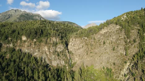 Carretilla-Aérea-Sobre-Corbata-Blanca-Cascada-De-Deshielo-Escondida-En-Bosques-De-Pinos-Y-Montañas,-Patagonia-Argentina