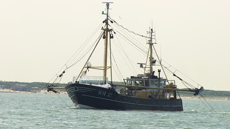 Fischerboot-Schleppnetze-Auf-See-An-Einem-Ruhigen-Tag-Mit-Strand-Im-Hintergrund