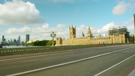 Bloqueo-En-Londres,-Ciclistas-Cruzan-El-Puente-Vacío-De-Westminster-Con-Las-Casas-Del-Parlamento-Al-Fondo,-Durante-La-Pandemia-De-Coronavirus-2020