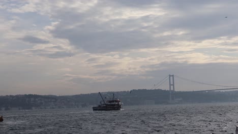 Boat-Cruising-Near-Bosphorus-Bridge-Which-Connects-Europe-And-Asia-In-Istanbul,-Turkey---wide-shot