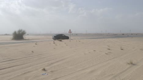 Black-Lamborghini-Urus-driving-on-highway-amid-desert-dunes-in-Dubai,-side-view