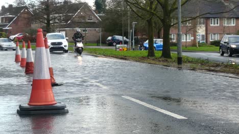 Storm-Christoph-scooter-driving-rainy-flooding-village-road-splashing-street-cones