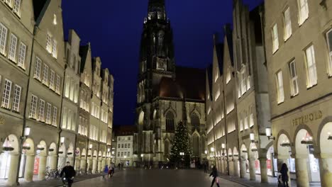 Kippen-Sie-Den-Schuss-Von-Wunderschönen-Beleuchteten-Stadtgebäuden-Und-Der-Berühmten-Hochhauskirche-St.-Lambert-Im-Hintergrund-Während-Des-Abends-Nach-Oben