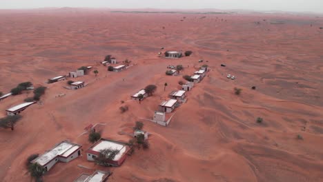 Rundschuss-Mit-Drohne-über-Touristen-In-Einem-Verlassenen,-Mit-Sand-Bedeckten-Dorf-In-Der-Wüste-Von-Dubai,-Vereinigte-Arabische-Emirate