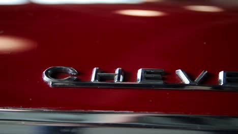 Aus-Der-Hand-Dolly-Aufnahme-Eines-Chevelle-Logos-Auf-Der-Motorhaube-Eines-Roten-Chevy