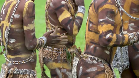 Bailarines-Tribales-Pintados-En-Decoración-De-Conchas-Frotan-Palos-En-Las-Manos,-Nueva-Guinea