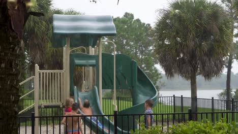 Young-boys-playing-on-a-slide-in-the-rain,-looking-out-of-a-window