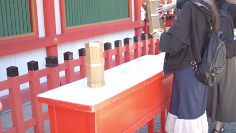 Girl-shaking-a-fortune-box-in-Kyoto,-Japan-soft-lighting-slow-motion-4K