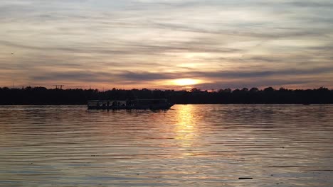 Bucharest,-Herastrau-lake,-9November:-A-dark-silhouette-boat-moving-on-the-lake-under-the-sunset,-reflected-on-the-water