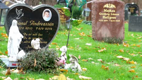 Lápida-Del-Joven-Con-Plantas-Y-Estatuas-Católicas-En-El-Cementerio-De-Kviberg-En-Gotemburgo,-Suecia