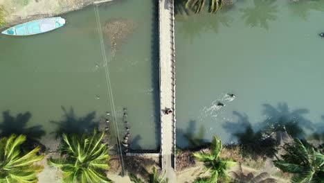 Two-people-couples-are-walking-along-the-river-over-a-concrete-bridge-with-a-fence-on-each-side