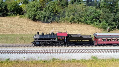 Aerial-View-of-a-Antique-Steam-Engine-Puffing-along-Pulling-Antique-Passenger-Cars-Through-Amish-Farm-Lands-on-a-Sunny-Autumn-Day-as-Seen-by-a-Drone