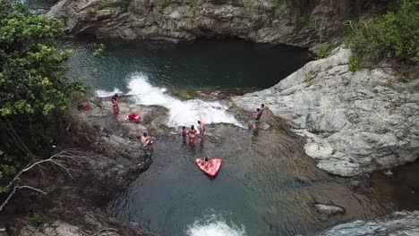 Menschen,-Die-Zwischen-Den-Kaskaden-Des-Wasserfalls-Charco-El-Ataud,-Puerto-Rico,-Luftaufnahme-Des-Bachwassers-Genießen,-Das-In-Natürliche-Pools-Fällt