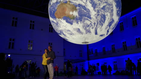 People-taking-pictures-in-front-of-a-surreal-looking-planet-Earth-rotating-inside-a-building-university