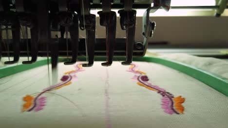 Modern-embroidery-machine-sewing-an-intricate-floral-design-in-orange,-pink-and-black