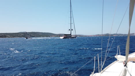 View-from-one-Sailboat-to-an-other-in-front-of-the-mainland-of-Sardinia,-Italy