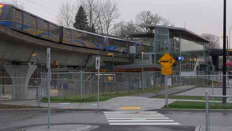 Millenium-Line-Train-Passing-At-The-Lafarge-Lake-Douglas-Station-In-Coquitlam,-Vancouver,-Canada-Early-In-The-Morning---Steady-Shot